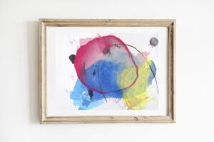 Colorful, abstract mixed media artwork in a light wood frame