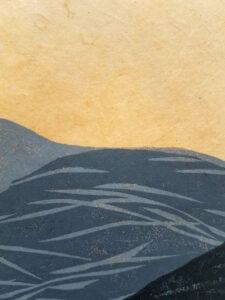 Detail of a woodcut print of an abstracted landscape with a moon above. The print is in shades of gray on light orange paper.