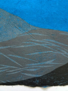 Detail of a woodcut print of an abstracted landscape with a moon above. The print is in shades of gray on blue paper.