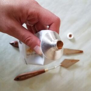 a hand holding a tube of handmade oil paint