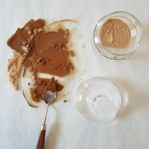 making oil paint with powdered ochre pigment, a palette knife, and a glass muller