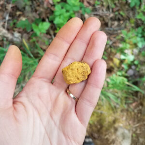 a hand holding a yellow rock